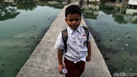 Seorang anak melintas di jalan setapak yang dibangun di atas air. 