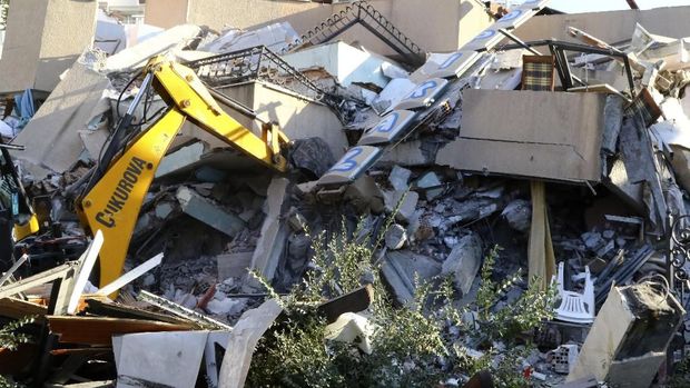 Sebuah buldoser dikerahkan untuk menyisir reruntuhan bangunan yang ambruk akibat gempa