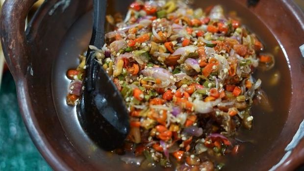 Sambal Matah, a popular salsa condiment of chopped chili peppers with lemon grass and shallots from Bali. The condiment is plated on old-fashioned crockery with red flowers paintings. It is served together with other popular spicy condiments from several other regions in Indonesia.