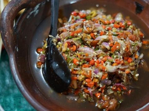 Sambal Matah, a popular salsa condiment of chopped chili peppers with lemon grass and shallots from Bali. The condiment is plated on old-fashioned crockery with red flowers paintings. It is served together with other popular spicy condiments from several other regions in Indonesia.