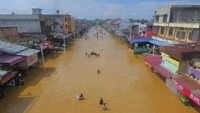 Warga melintasi banjir yang menggenangi Kota Pasir Pangaraian, Rokan Hulu, Riau, Selasa (26/11/2019). Banjir yang semakin meluas di Rohan Hulu itu memutus akses jalan utama di wilayah tersebut. ANTARA FOTO/Humas Rokan Hulu.