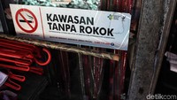 Poster larangan merokok juga tertempel di jendela dan dinding rumah yang berada di bantaran sungai kecil. 