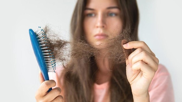 rambut rontok Young woman is very upset because of hair loss