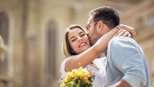 Picture of young man surprising woman with flowers