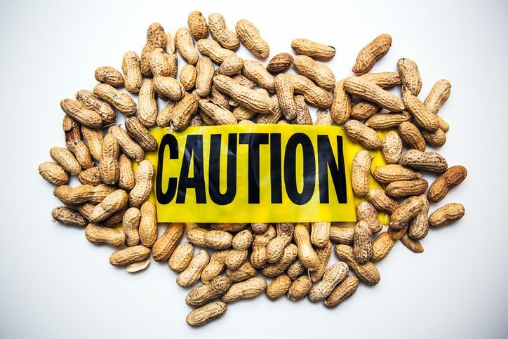 Many peanuts with a syringe and a bottle of medication for allergy on a wood tablecloth