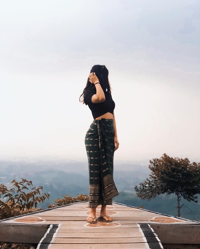 Karen tampaknya menyukai baju tradisional. Dalam foto berikut ia mengenakan kain sebagai rok untuk dipadankan dengan kaus crop top. Foto: Instagram @karbearv