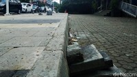 Tampak beberapa konblok beton ditumpuk untuk memudahkan pengendara sepeda motor masuk ke halaman gedung.