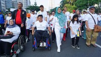 Juliari mengikuti jalan sehat sambil mendorong dan berbincang dengan salah satu peserta di kursi roda. Istimewa/Kemensos.