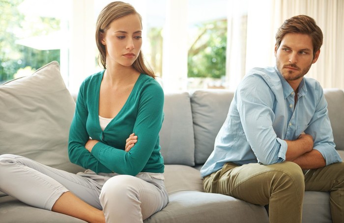 zodiak Focused man and woman sit on couch using laptop taking care of financial bills, husband and wife manage bank documents, reading regulations online, upset couple consider received papers