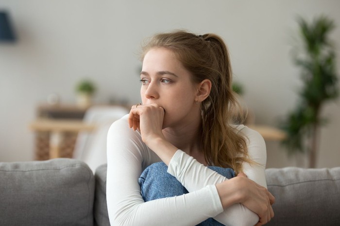 Head shot woman anxious worried woman sitting on couch at home. Frustrated confused female feels unhappy, problems in personal life, quarrel break up with boyfriend and unexpected pregnancy concept