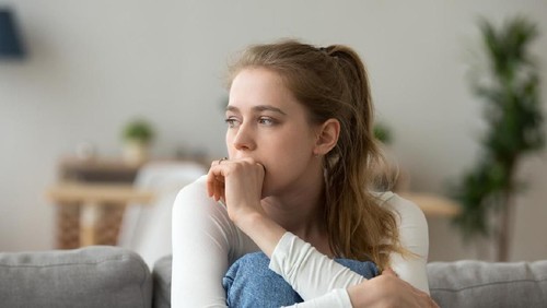 Head shot woman anxious worried woman sitting on couch at home. Frustrated confused female feels unhappy, problems in personal life, quarrel break up with boyfriend and unexpected pregnancy concept