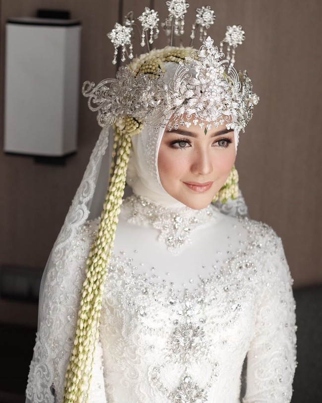 Makeup yang diterapkan Ernia Aprilia dari Redberry Wedding membuat Citra Kirana tampak manglingi, namun tetap menonjolkan kecantikan wajah aslinya. Ditambah lagi dengan hiasan kepala kha Sunda, siger dan rangkaian ronce melati yang memanjang disampirkan ke depan, penampilan aktris 25 tahun itu semakin bak bidadari. Foto: Dok. Instagram Anchawedding, Redberrywedding