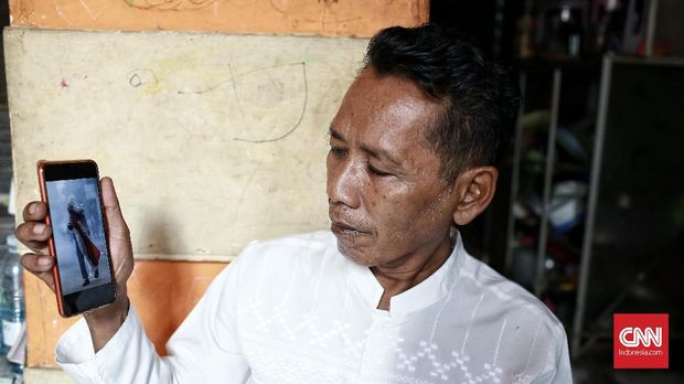 Budi Sulistyo (55), menunjukkan foto Luthfi Alfiandi yang tengah membawa bendera.