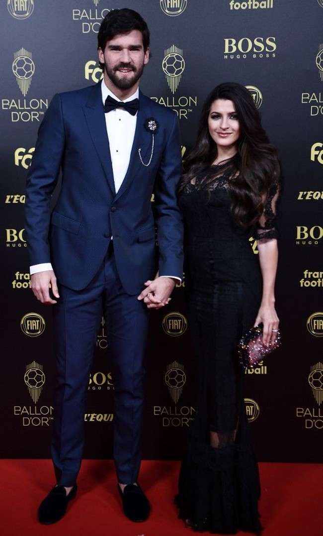 Kiper Liverpool Alisson Becker menghadiri Ballon dOr bersama istrinya, Natalia Loewe Becker. Natalia Loewe Becker yang merupakan seorang dokter itu tampil memesona dengan rambut ikal panjangnya yang digerai dan memakai gaun hitam dengan detail transparan di bagian kaki. Foto: Anne-Christine POUJOULAT / AFP