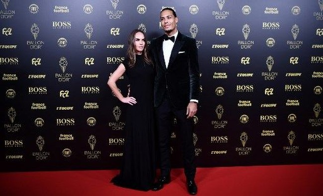 Pemain Liverpool lainnya yang juga hadir di pesta Ballon dOr adalah Virgil van Dijk. Virgil termasuk salah satu kandidat pemenang Ballon dOr. Dia pun didampingi istrinya Rike Nooitgedagt yang memesona. Rike yang rela meninggalkan pekerjaannya di dunia fashion demi mengikuti karier suami tampil elegan dengan gaun hitam simpel yang panjangnya menyapu lantai. Foto: Anne-Christine POUJOULAT / AFP