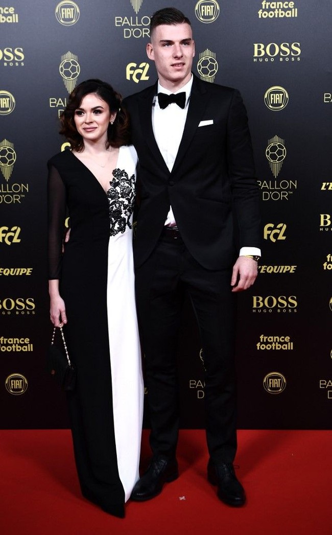 Pemain sepakbola Ukraina Andriy Lunin menghadiri upacara penghargaan Ballon dOr France Football 2019 ditemani kekasihnya, Nastasica. Wanita cantik itu memakai gaun hitam putih yang serasi dengan gaya sang kekasih. Gaunnya yang monokrom dipercantik dengan detail bunga di bagian dada. Foto: Anne-Christine POUJOULAT / AFP