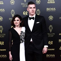 Pemain sepakbola Ukraina Andriy Lunin menghadiri upacara penghargaan Ballon dOr France Football 2019 ditemani kekasihnya, Nastasica. Wanita cantik itu memakai gaun hitam putih yang serasi dengan gaya sang kekasih. Gaunnya yang monokrom dipercantik dengan detail bunga di bagian dada. Foto: Anne-Christine POUJOULAT / AFP