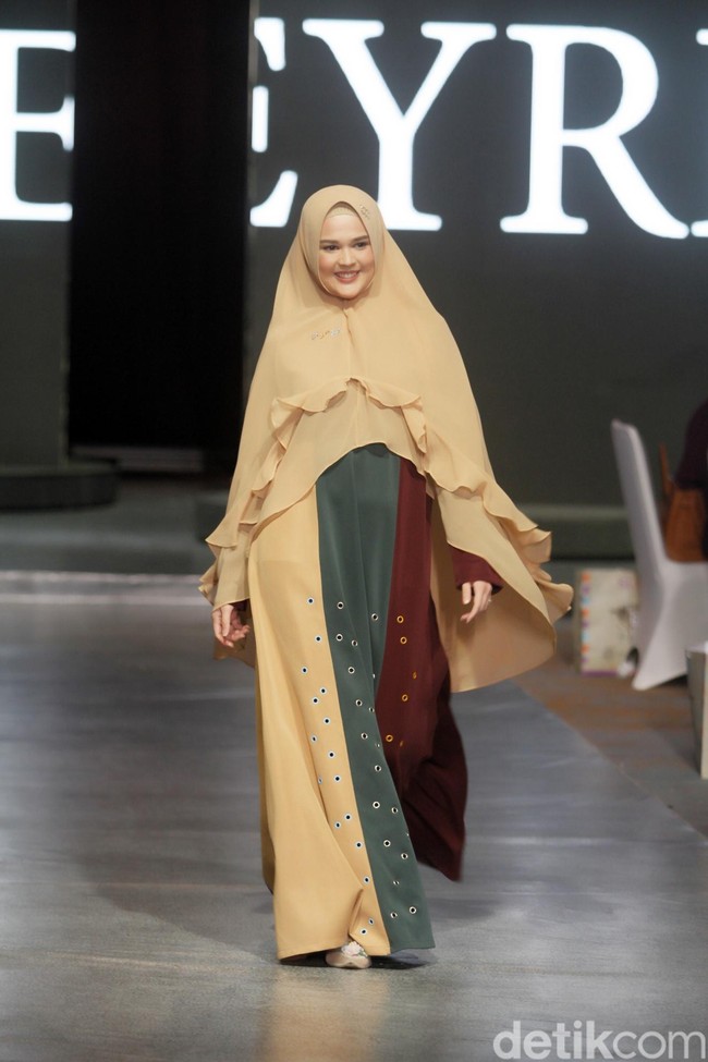 Cut Meyriska berlenggang bak model dengan abaya coklat hijau. Khimar dengan keliman bergaya ruffle menyumbangkan kesan feminin pada penampilannya. Foto: Mohammad Abduh/Wolipop