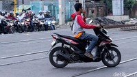 Selain menerobos palang kereta api, ada pula pengendara yang tak mengenakan helm dan perlengkapan keselamatan berkendara lainnya saat melintas di jalanan.