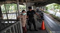 Petugas TransJajarta juga membantu menyeberangkan warga.