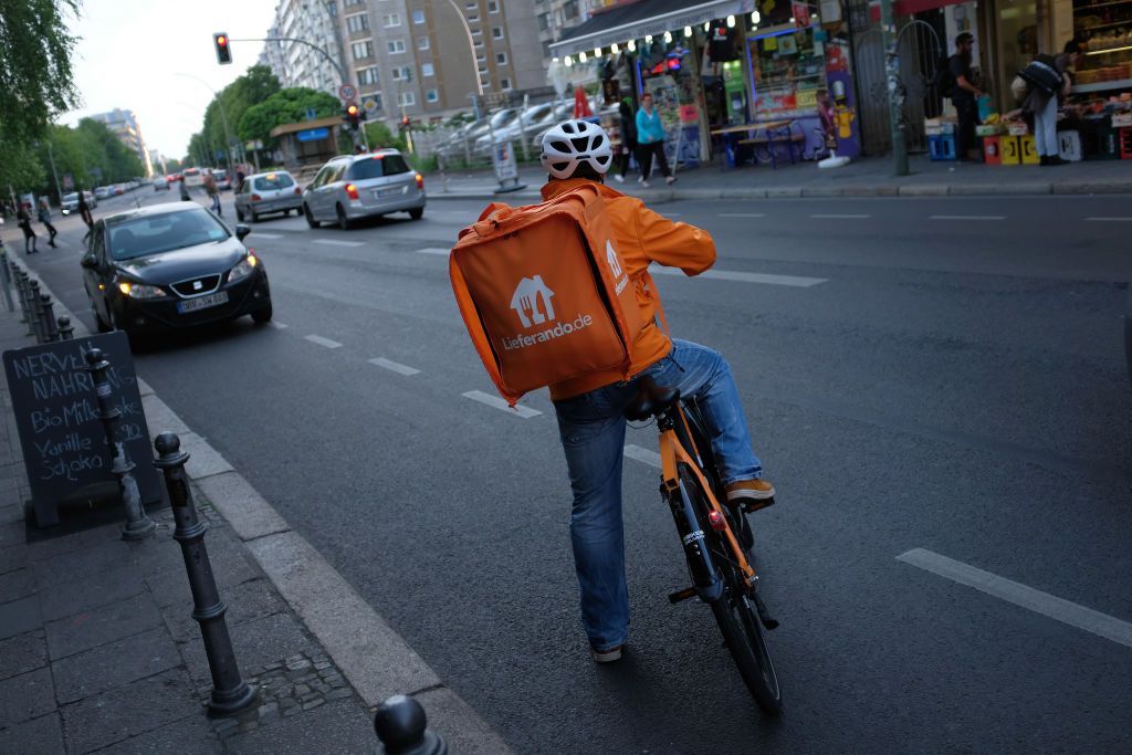 BERLIN, GERMANY - MAY 17: A man riding a bicycle for food delivery service Lieferando prepares to enter traffic on May 17, 2018 in Berlin, Germany. A variety of food delivery setvices, including Lieferando, Deliveroo, Foodora and others, have established themselves across Germany. All depend heavily on part-time workers who receive little to no benifits. Some riders have sought to organize themselves into works councils, efforts that have so far failed or been thwarted by the companies.   (Photo by Sean Gallup/Getty Images)