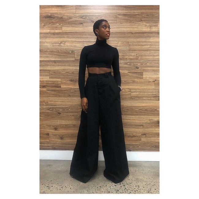 Salah satu gaya andalan Lashana Lynch: all black. Crop top yang mengekspos perut ratanya menjadikan gaya berwarna polos tersebut tetap menarik. (Foto: Instagram/@lashanalynch)