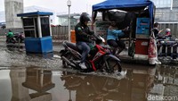 Seorang pemotor melintasi jalan yang tergenang air di kawasan Boulevard Kelapa Gading, Jakarta Utara.