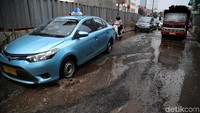 Sejumlah kendaraan melintasi jalan yang rusak dan tergenang air di kawasan Boulevard Kelapa Gading, Jakarta Utara, Jumat (12/6/2019).