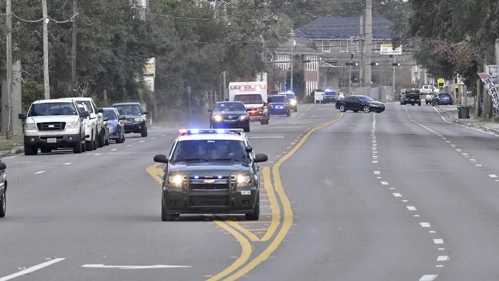 Police cars escort an ambulance after a shooter open fire inside the Pensacola Air Base, Friday, Dec. 6, 2019 in Pensacola, Fla.   The US Navy is confirming that a shooter is dead and several injured after gunfire at the Naval Air Station in Pensacola. (Tony Giberson/ Pensacola News Journal via AP)
