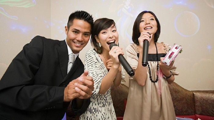 young woman holding microphone and singing at karaoke
