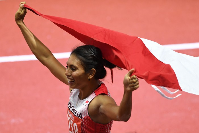 Atlet lompat jauh Indonesia Maria Natalia Londa membentangkan Bendera Merah Putih setelah berhasil memenangkan pertandingan Final Lompat Jauh Putri SEA Games ke-30 di Stadion Atletik New Clark, Filipina, Minggu (8/12/2019). Maria Natalia Londa berhas