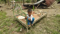 Seorang anak berada disekitar rumahnya yang rusak dan terendam lumpur akibat diterjang banjir bandang di Desa Poi, Kabupaten Sigi, Sulawesi Tengah, Minggu (8/12/2019).