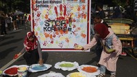 Warga ramai-ramai membubuhkan cap tangan sebagai bentuk partisipasi. Aksi tersebut juga untuk memperingati Hari Anti Korupsi Sedunia.