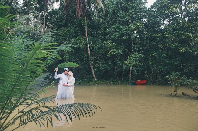 Pemotretan kreatif ini pun memperlihatkan romansa pengantin di tengah banjir yang tak memedulikan pakaian mereka yang sebagian basah terkena air. Foto: Facebook Meen Photographer