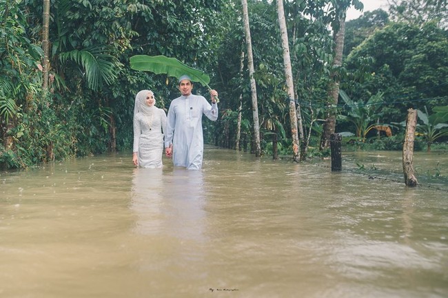 Pasangan di Thailand Selatan mencuri perhatian setelah memutuskan untuk tak membiarkan cuaca meredam perayaan istimewa pernikahan mereka. Meskipun harus berjibaku dengan air banjir pasangan pengantin ini tetap bahagia. Foto: Facebook Meen Photographer