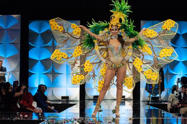 Finalis Miss Universe 2019 dari US Virgin Islands Andrea Piecuch tampil heboh bak kupu-kupu raksasa. Dia mengenakan sayap dengan hiasan bunga berwarna kuning dan hiasan kepala yang dilengkapi rumbai hijau. Foto: Facebook Miss Universe