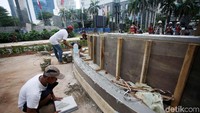 Dua orang pekerja sedang merampungkan pembangunan konstruksi amphiteater.