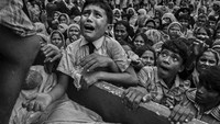 Seorang anak menangis ketika dia naik ke atas sebuah truk yang mendistribusikan bantuan di dekat kamp pengungsi Balukhali, Coxs Bazar, Bangladesh, pada 20 September 2017. Di Bangladesh, para pengungsi ditempatkan di kamp-kamp yang ada dan permukiman sementara. Kondisi menjadi kritis; pelayanan dasar berada di bawah tekanan parah dan kebanyakan orang kekurangan air bersih, tempat tinggal dan sanitasi. Kevin Frayer/Getty Images.
