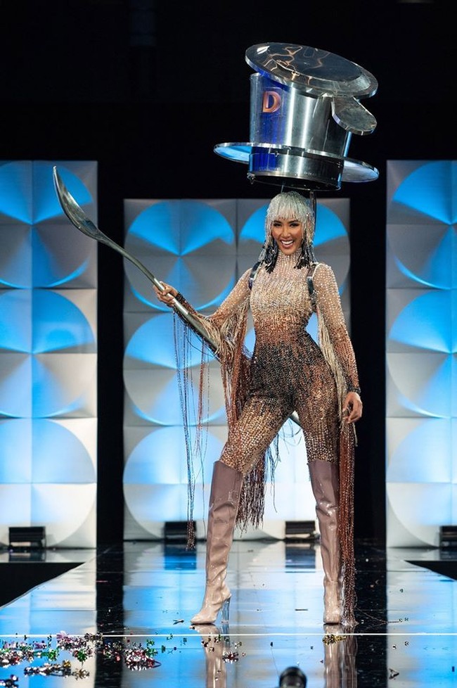Miss Vietnam Hoàng Thùy memakai kostum nasional berbentuk teko kopi Vietnam plus sendoknya di ajang Miss Universe 2019. Mia Hong tampil memakai teko kopi Vietnam ukuran raksasa di atas kepalanya. Dia juga memegang sendok raksasa. Sedangkan busana, Mia mengenakan jumpsuit bertabur bebatuan kristal yang berkilauan. Rambutnya memakai wig ala Cleopatra. Foto: Facebook Miss Universe