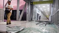Seorang pengunjung melintas diantara pecahan kaca dari jendela Skybridge di Stasiun Balapan, Solo, Jawa Tengah, Selasa (10/12/2019) akibat angin ribut.
