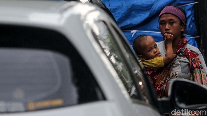 Penyandang Masalah Kesejahteraan Sosial (PMKS) mengamen di Jalan Cideng Barat, Jakarta. Dia tampak menggendong anak kecil.