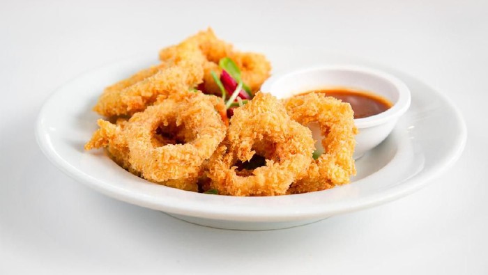 Fried crispy squid rings breaded ( caramari ) with red sauce on white backgruond