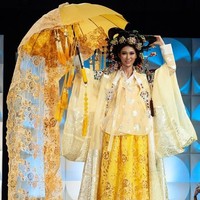 Miss Korea Selatan Lee Yeon Ju mengenakan busana khas negaranya hanbok berwarna kuning. Wanita 25 tahun itu melengkapi gayanya sehingga terlihat heboh dengan membawa payung yang dihiasi kain panjang hingga menyapu lantai. Penampilan Lee Yeon Ju mirip pengantin di Korea. Foto: Facebook Miss Universe