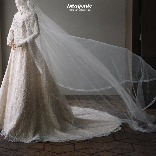 Tidak ketinggalan veil panjang yang menjuntai dari hijabnya kian memaksimalkan gaya Citra Kirana yang berkonsep pengantin modern. Riasan wajah polesan Bennu Sorumba ikut menyempurnakan momen gaya sang pengantin. (Foto: Instagram/@citrakirana)