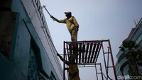 Dengan menggunakan alat bantu, para petugas Bina Marga mengecat seluruh bagian dinding JLNT Antasari-Blok M tersebut.
