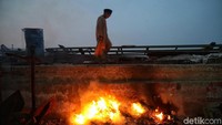 Seorang anak melintas di sekitar sampah yang dibakar oleh warga sekitar.