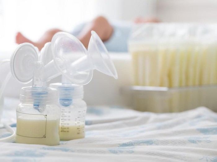 Breast milk frozen in storage bag and baby lying on background