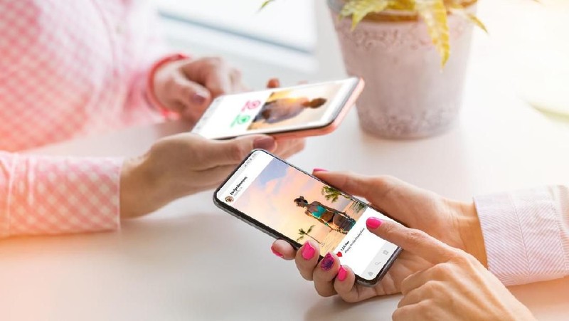 Two unrecognisable Caucasian ethnicity females using their mobile phones together