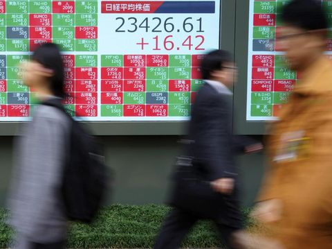 People walk past an electronic stock board showing Japan's Nikkei 225 index at a securities firm in Tokyo Wednesday, Dec. 11, 2019. Asian stock markets have risen following a report President Donald Trump plans to delay a tariff hike on Chinese goods. (AP Photo/Eugene Hoshiko)