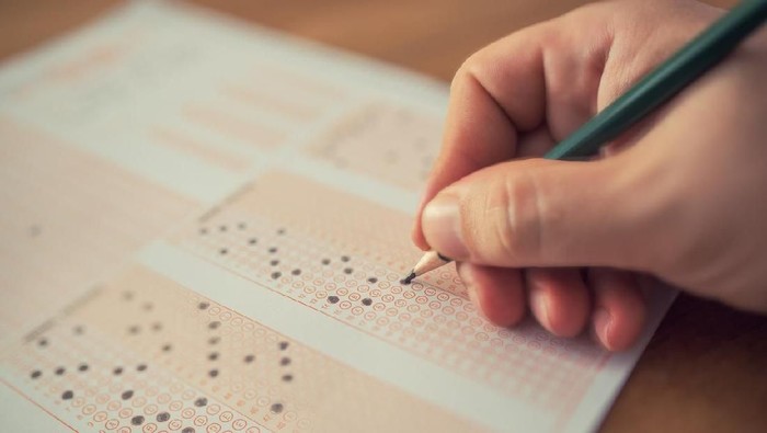 Education school test concept : Hands student holding pencil for testing exams writing answer sheet or exercise for taking fill in admission exam multiple carbon paper computer at university classroom